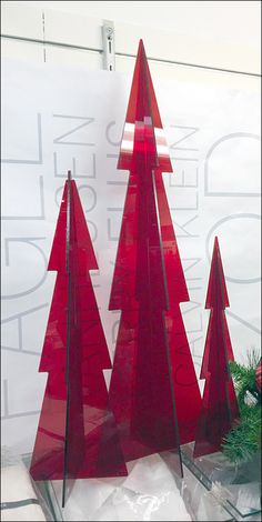 three red glass christmas trees sitting on top of a table