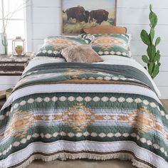 a bed with a green and white comforter next to a painting on the wall