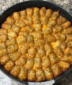 a pan filled with tater tots and cheese on top of a granite counter