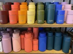 many different colored coffee mugs are stacked on the shelf in front of each other