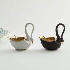 three ceramic swan shaped teapots sitting next to each other on a white surface