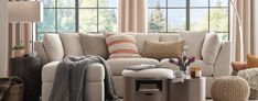 a living room filled with lots of furniture and pillows on top of a rug next to a window