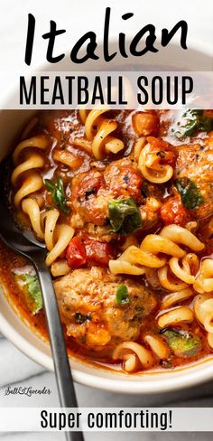 a white bowl filled with meatball soup and pasta on top of a marble table