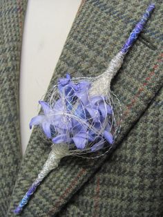 a boutonniere with blue flowers attached to the lapel of a suit jacket