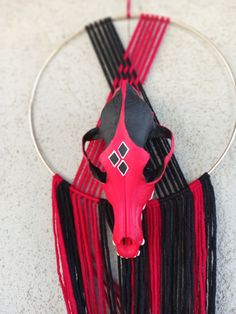 a cow's head hanging from a hoop with fringes on the bottom of it