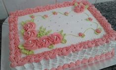 a cake with pink frosting and flowers on it sitting on a counter top next to a tile wall