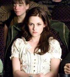 a woman sitting in front of two other people at a movie theater with drinks and popcorn