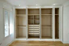 an empty closet with white shelves and drawers in the middle, next to a window