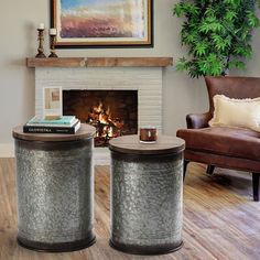 two metal stools sitting next to each other in front of a fire place with a painting on the wall