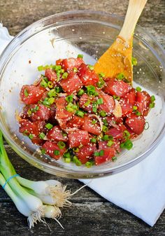 a bowl filled with meat and vegetables on top of a wooden table next to garlic