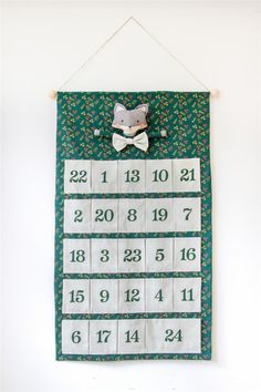 a wall hanging calendar with a teddy bear on it's back and numbers in the middle