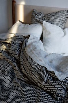 an unmade bed with white pillows and black checkered blankets on top of it