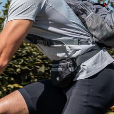 a man with a back pack is riding on his bike in front of some bushes