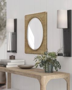 a wooden table topped with a vase filled with flowers next to a wall mounted mirror