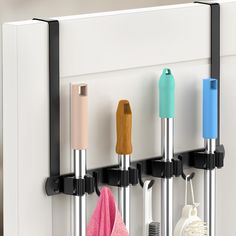 three different colored kitchen utensils hanging on a white wall with black handles and hooks