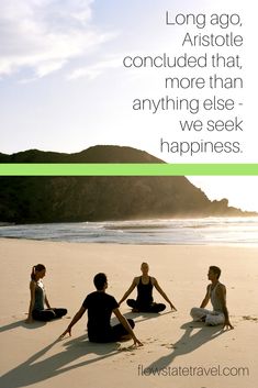 three people are sitting on the beach in front of the ocean and one person is doing yoga