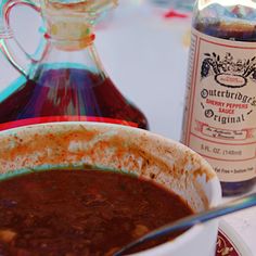 a bowl of chili next to a bottle of wine