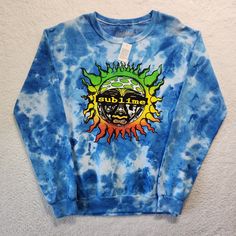 This Sublime sweatshirt is the perfect addition to any music lover's collection. With its blue tie-dye pattern and graphic print featuring the Sublime logo, this sweatshirt is sure to turn heads. The pullover style and crew neckline provide both comfort and style, while the long sleeves make it suitable for any season. It's made from a blend of polyester and cotton, which ensures it's machine washable and durable. This sweatshirt is a regular fit and is available in size small. It's a Band Tees Sublime Sweatshirt, Sublime Logo, Tie Dye Sweatshirt, Tie And Dye, Tie Dye Patterns, White Tie, Blue Tie Dye, Blue Ties, Crop Sweatshirt