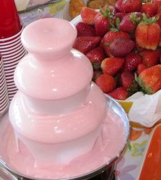 some strawberries and other food items on a table with pink liquid in the middle