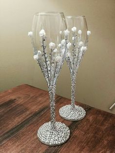 two wine glasses sitting on top of a table next to each other with pearls in them