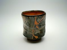 a black and brown cup with red designs on the inside is sitting on a white surface