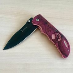 a pink and black knife sitting on top of a wooden table