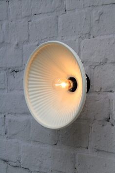 a light that is on the side of a wall next to a white brick wall