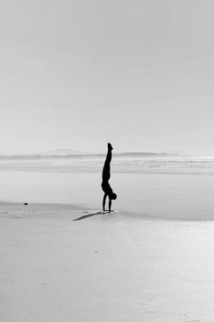 a person doing a handstand on the beach