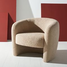 a beige chair sitting in front of a red and white wall