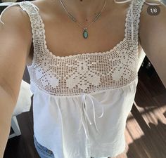 a close up of a person wearing a white shirt and blue jeans with a necklace