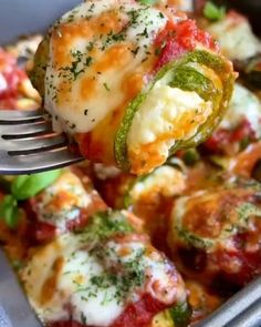 a fork full of food that is being lifted from a casserole dish with cheese and vegetables