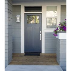 a blue front door on a gray house with purple flowers in the window box and white trim