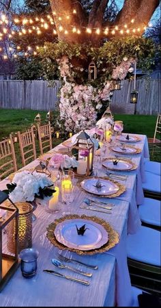 an outdoor dinner table set up with candles, plates and place settings for the guests