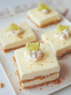 four pieces of cake with white frosting and green garnish on top sitting on a plate