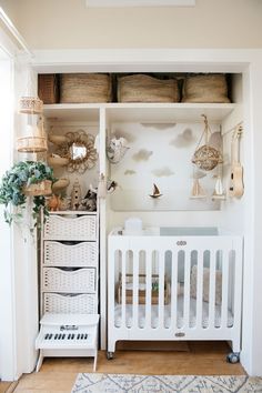 a baby's room with white furniture and baskets on the shelves, including a crib