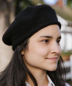 a woman with long hair wearing a black knitted hat and smiling at the camera