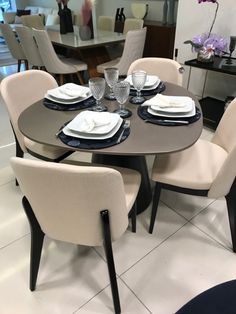 a dining room table set for six with white and black plates on the centerpiece