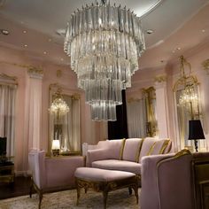 a fancy living room with pink couches and chandelier hanging from the ceiling