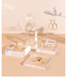 three clear acrylic boxes with rings and earrings in them on top of a table