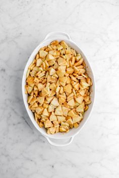 a bowl filled with chopped apples on top of a marble counter