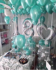 balloons and streamers are hanging from the ceiling in front of a table with a cake on it