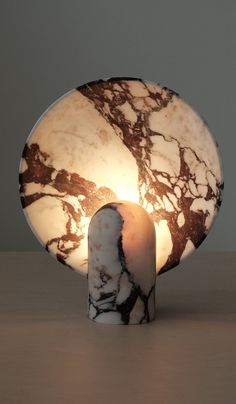 a table lamp with a marbled surface on it's base and a light bulb in the middle