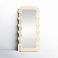 a white mirror sitting on top of a table next to a wall mounted shelf with an ornate frame