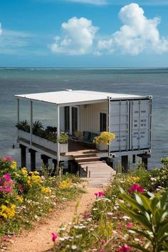 a house made out of shipping containers sitting on top of a hill next to the ocean