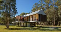 a modern house in the middle of a field with trees and grass on both sides