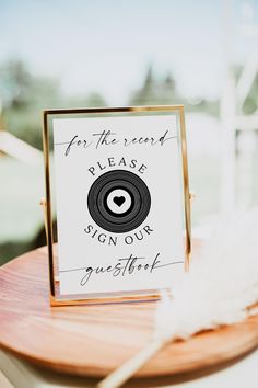 a sign that says for the record please sign our guests on it is sitting on a wooden table