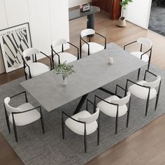 a dining table with white chairs and a plant on it in a living room area