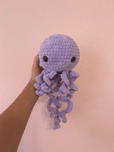 a hand holding up a crocheted purple octopus