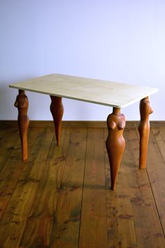 a white table with three wooden legs on the floor