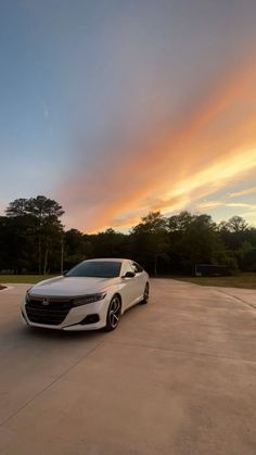 a white car parked on top of a parking lot under a cloudy blue and orange sky